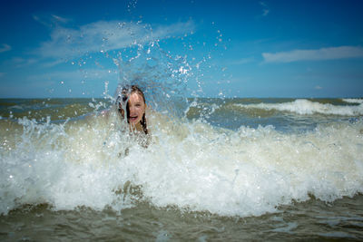 Man splashing water in sea against sky