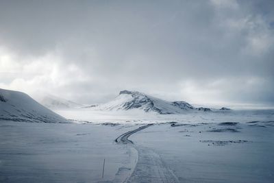 Scenic view of snow covered mountains against cloudy sky