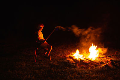 Side view of man holding bonfire at night