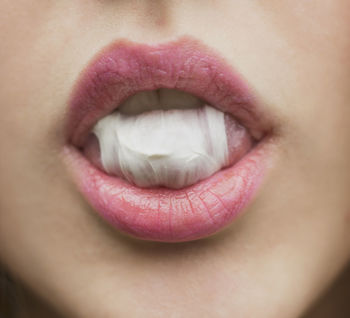 Close-up of woman with pink lipstick eating bubble gum