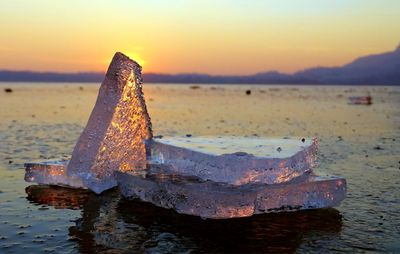 Close-up of ice cubes at beach during sunset