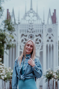 Portrait of smiling young woman standing against ornate building