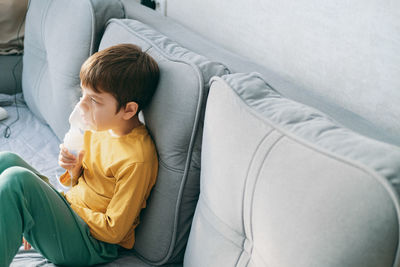 High angle view of boy sleeping on sofa at home