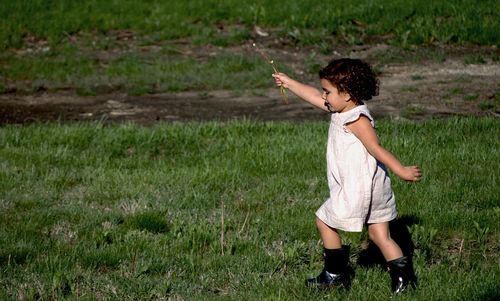 Side view of girl running on grassy field