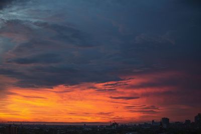 Silhouette buildings against dramatic sky during sunset