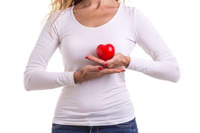 Midsection of woman holding heart shape against white background