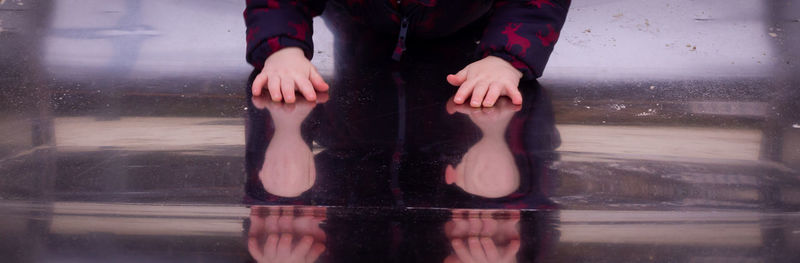 A toddlers hands reflecting on a metal slide 
