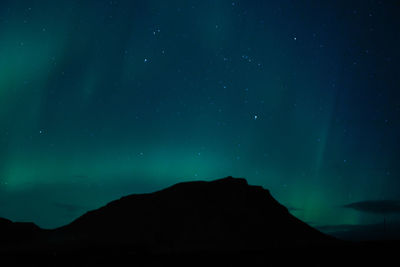 Low angle view of silhouette mountain against sky at night