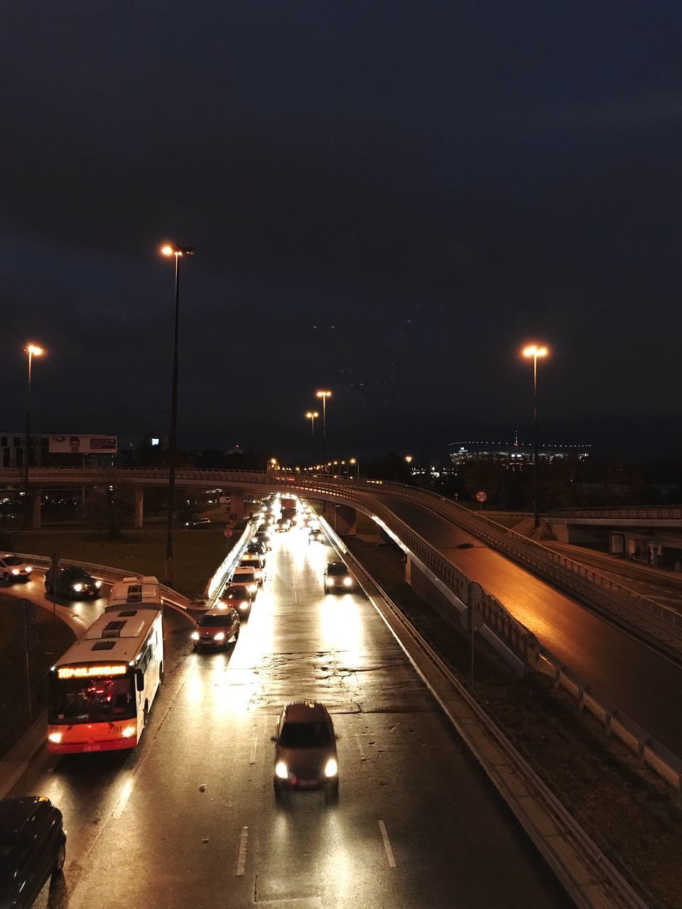 CARS ON ILLUMINATED CITY STREET AT NIGHT