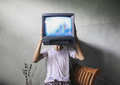 Rear view of boy standing against wall at home