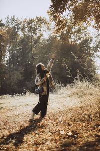 Girl with hand raised standing in autumn forest