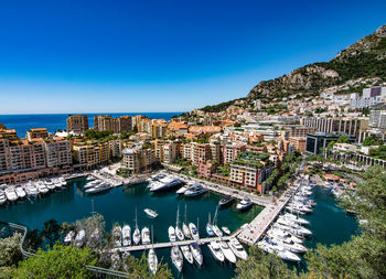 High angle view of city by sea against clear blue sky