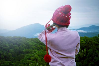 Rear view of man looking at mountain against sky