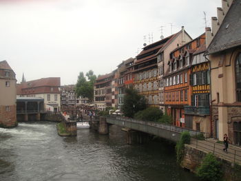 Buildings by river in town against sky