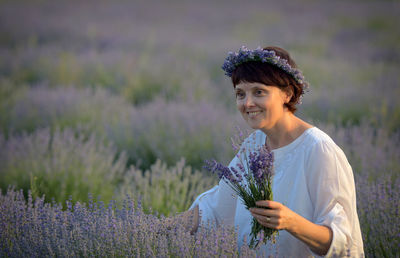 Smiling woman standing amidst flowering plants