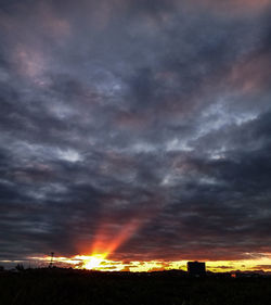 Silhouette landscape against dramatic sky during sunset