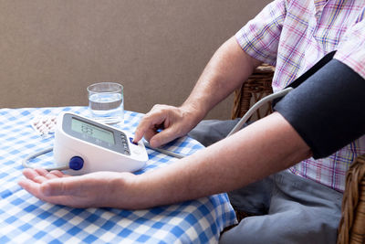 Midsection of man holding glass while sitting at home