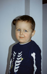 Portrait of cute boy standing against wall