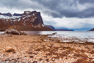 Scenic view of sea by mountains against sky