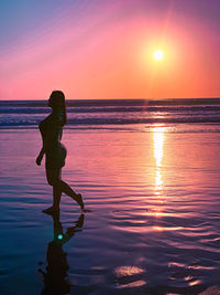 Side view of woman walking on beach during sunset