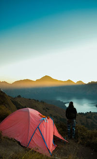 Rear view of woman standing by tent on field