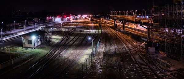 High angle view of railroad tracks in illuminated city at night