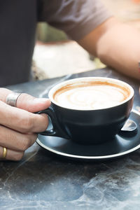 Midsection of man having coffee on table at outdoor cafe