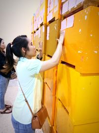 Side view of woman standing against yellow umbrella