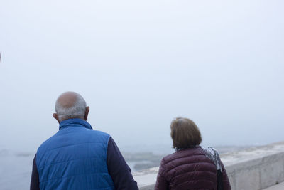 Rear view of couple looking at sea during foggy weather