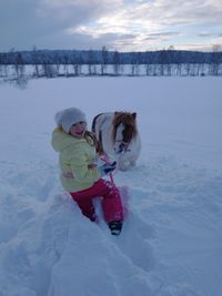 Woman with umbrella on snow field against sky