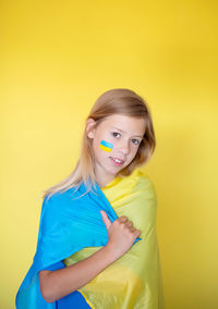 Portrait of young woman against yellow background