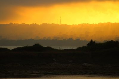 Scenic view of silhouette field against sky during sunset