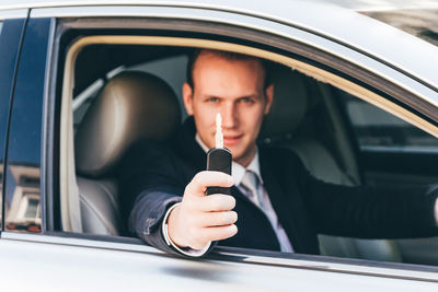 Portrait of businessman holding key while sitting in car