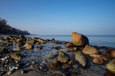 Scenic view of sea and rocks against clear sky