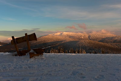 Scenic view of snow covered field against sky during sunset