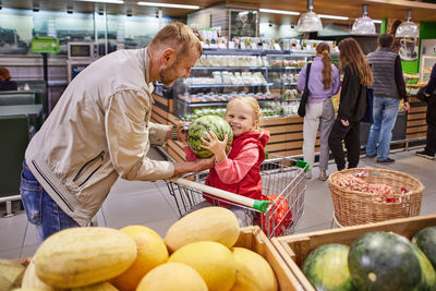 Father and daughter carrying watermelon at supermarket