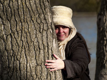 Portrait of woman embracing tree trunk