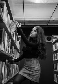 Young woman reading book in library