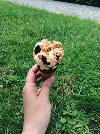 Close-up of hand holding ice cream cone on field