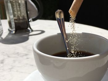 Close-up of sugar pouring in coffee cup