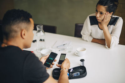 Man using mobile phone while sitting on table