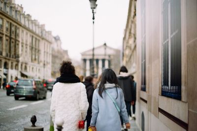 Rear view of people walking on street in city