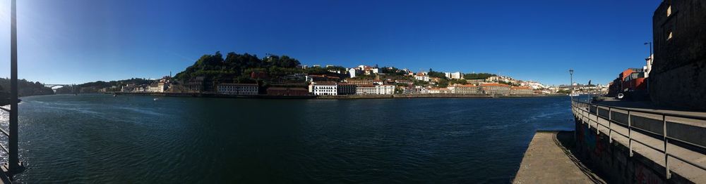 Panoramic shot of townscape by sea against clear blue sky