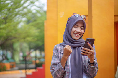 Portrait of young woman standing against trees