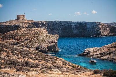 Scenic view of sea by cliff against sky