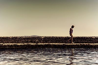 Full length of man standing on sea against clear sky