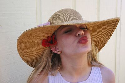 Close-up of young woman puckering lips while standing against wall