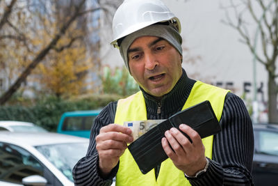 Engineer in reflective clothing looking at wallet