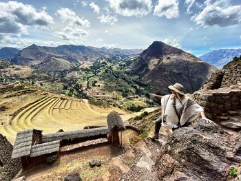 Panoramic view of people sitting on mountain against sky