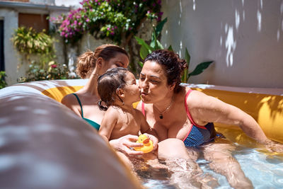 A girl, a grandmother and a little girl are playing in an inflatable pool. vacation concept